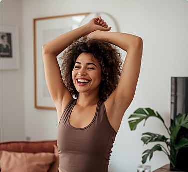Woman smiling and stretching arms overhead at home