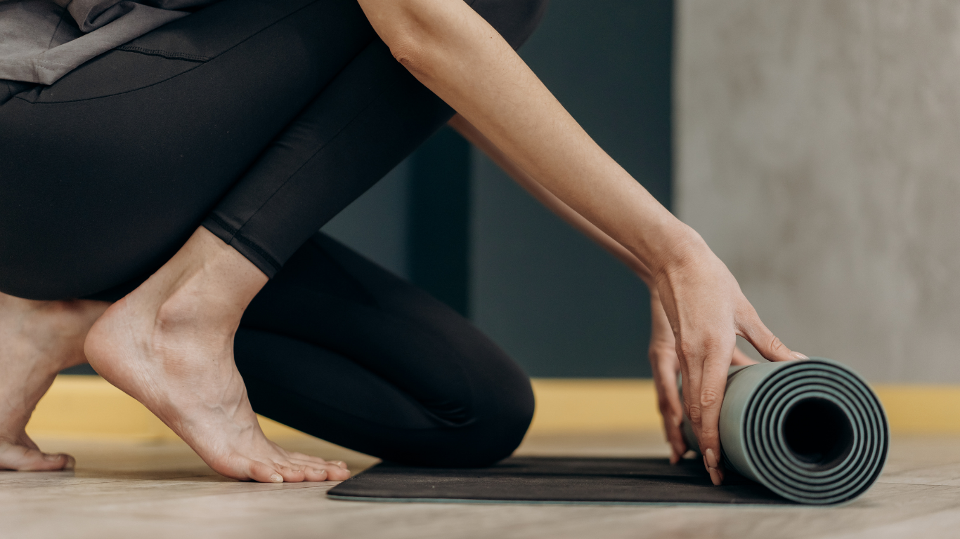 Close-up of hands rolling up a yoga mat